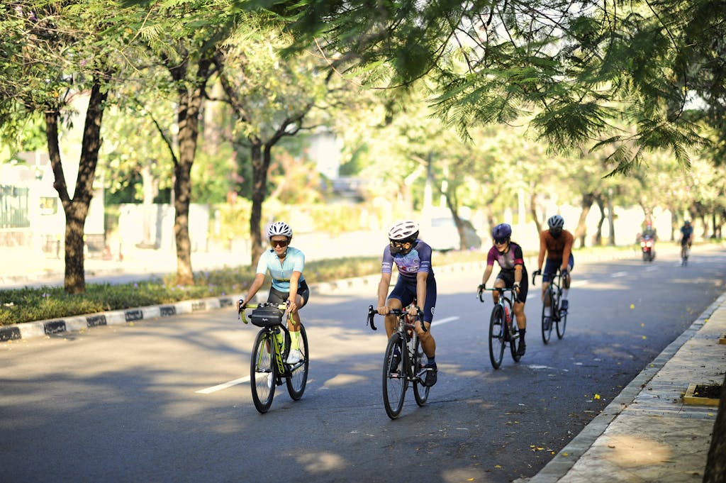 Cyclists enjoying a sunny ride through leafy roads in Jakarta, Indonesia.
